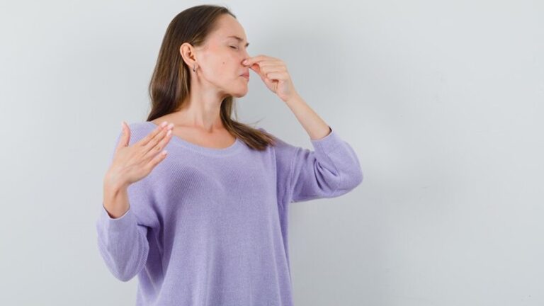 a woman pinching her nose because of musty odor in her house.