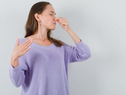 a woman pinching her nose because of musty odor in her house.