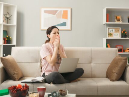 woman sitting on couch and covering her nose with hands, she might be smelling something must odor in her house.